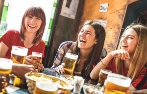 Happy girlfriends women group drinking beer at brewery bar restaurant Friendship concept with young female friends enjoying time and having genuine fun at cool vintage pub Focus on left girl