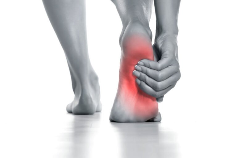 Woman holding her painful foot on white background